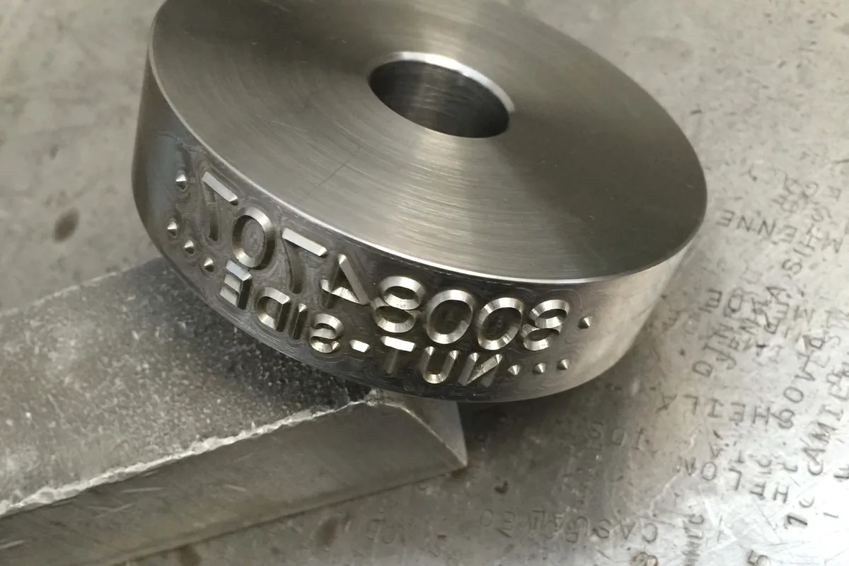 Roll die close-up with engraved production marking detail.
